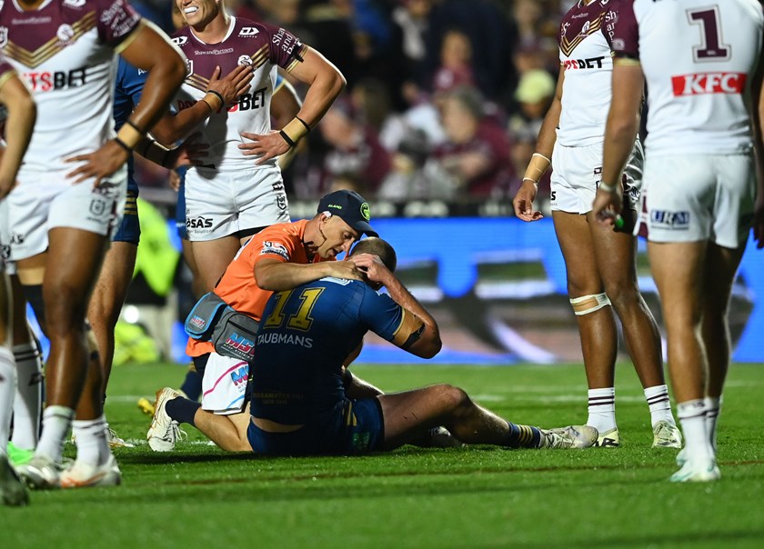 Shaun Lane receives treatment after the tackle from Manly's Haumole Olakau'atu and Daly Cherry-Evans.
