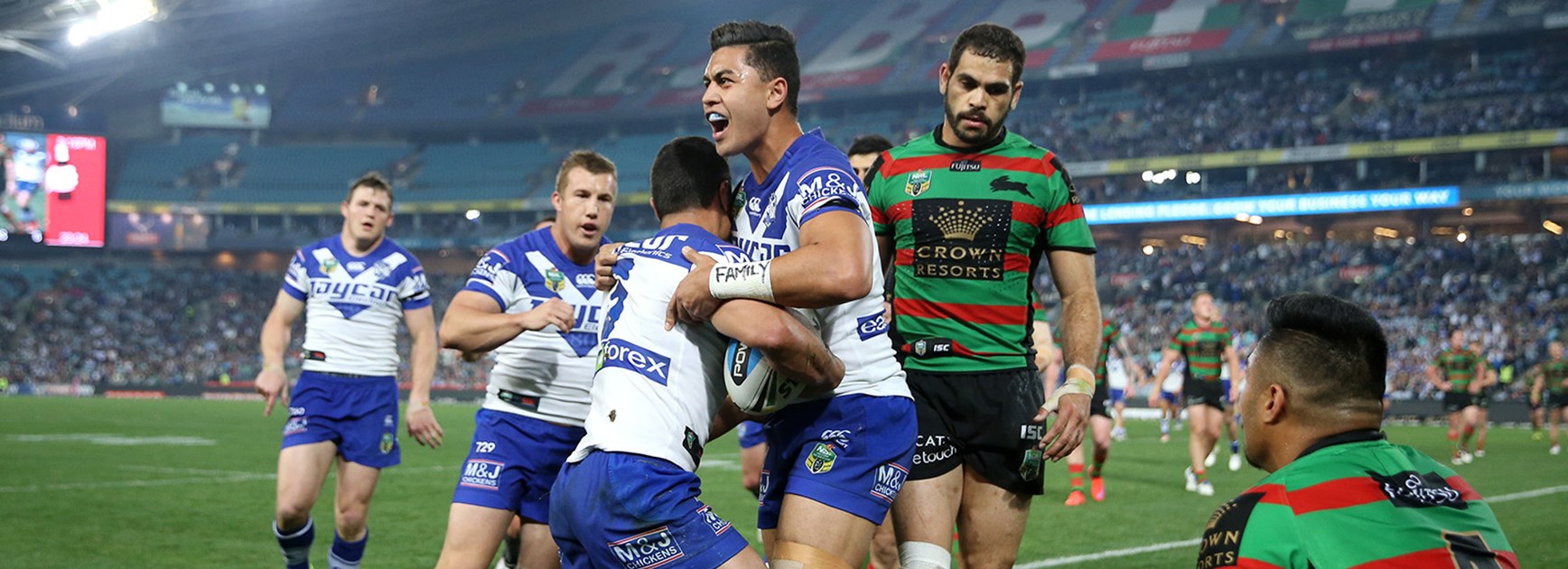 Bulldogs players celebrate another try as Greg Inglis looks on dejected.