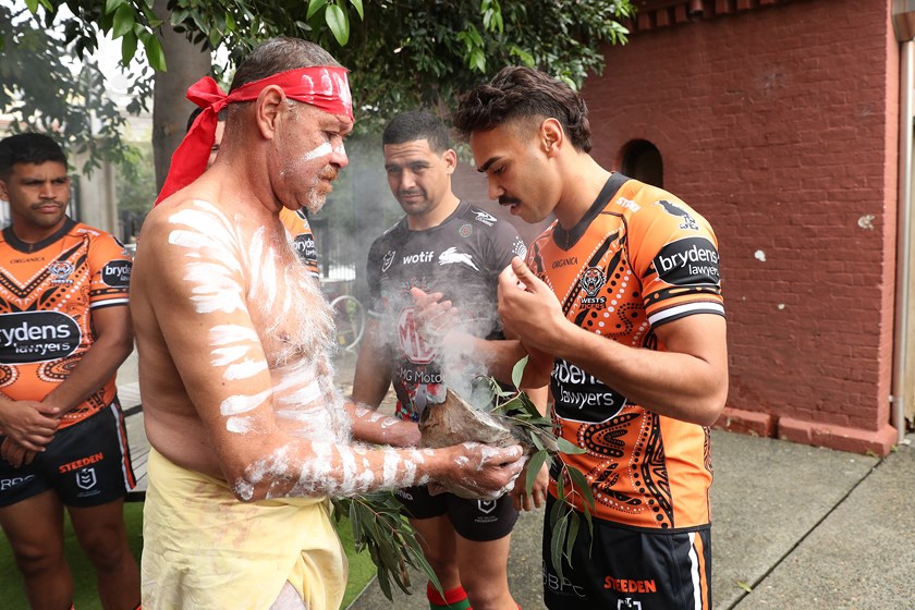 Walker looks on as Laurie takes part in a smoking ceremony at the Indigenous Round launch 