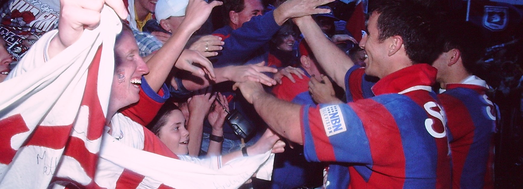 Johns celebrates with Newcastle fans after their upset win in the 1997 grand final.