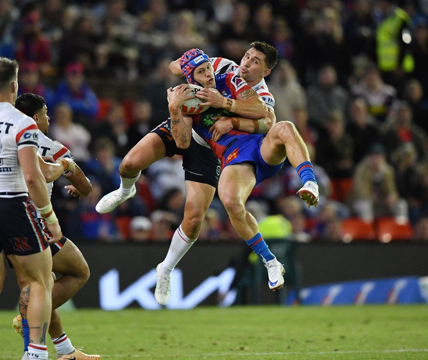 Kalyn Ponga is taken in a mid-air tackle by Victor Radley.