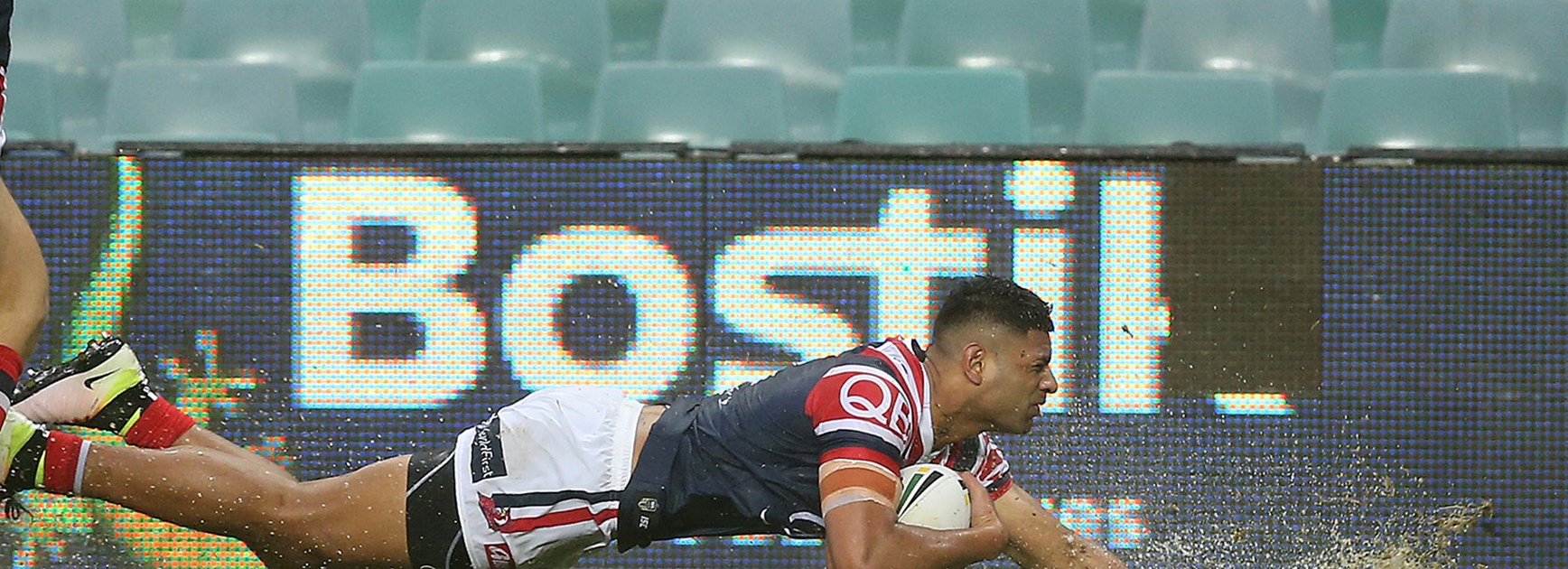 Daniel Tupou splashes over for the Roosters against the Wests Tigers at a wet Allianz Stadium.