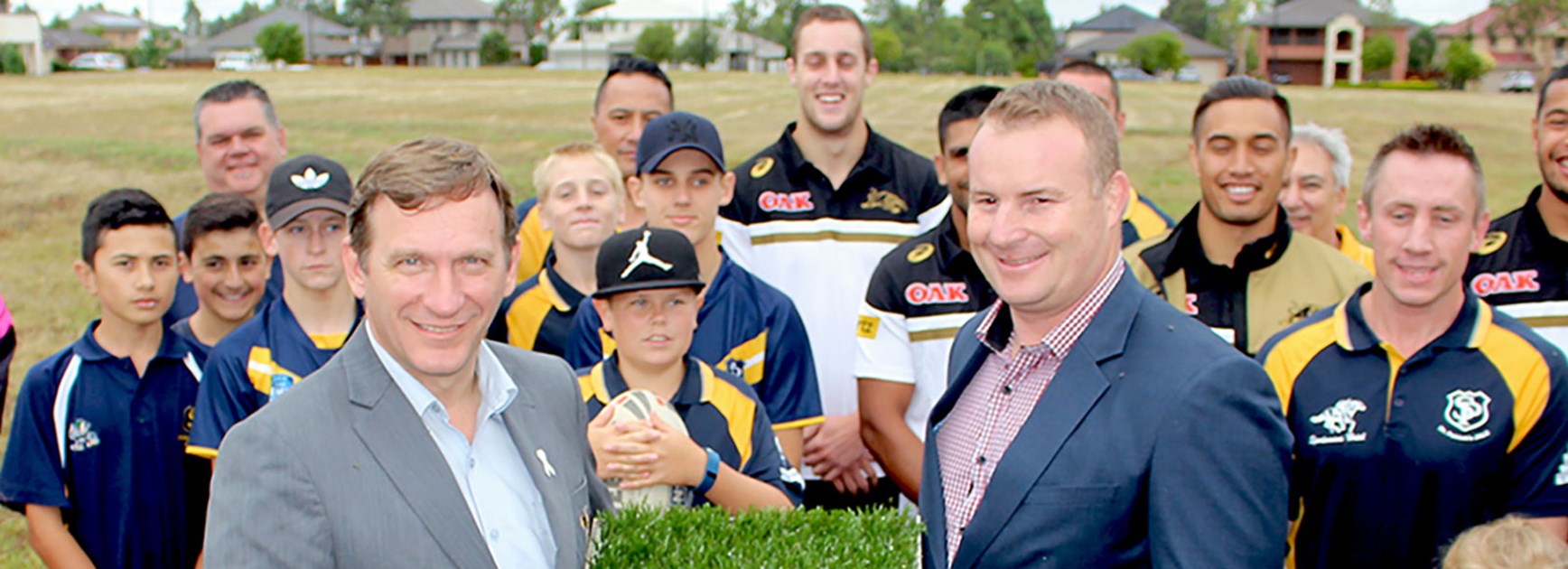 Blacktown Mayor Stephen Bali and NRL Player Development Manager John Wilson, members of St Patricks Junior Rugby League Club, Penrith Panthers players and a sample of the new surface.
