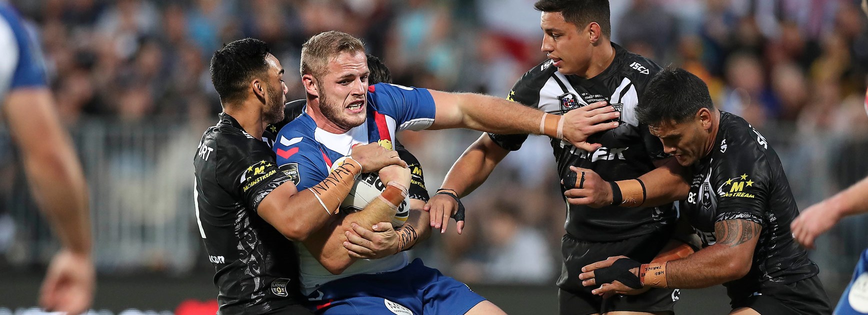Tom Burgess is tackled by the Kiwis.