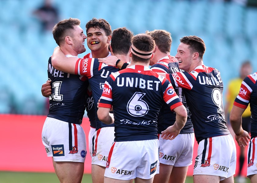 Latrell Mitchell is swamped by Roosters teammates after scoring a try.