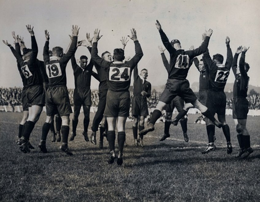 Brown (wearing No. 14 with his back to the camera) leaps like a veritable Kangaroo whilst performing the war cry in 1933.